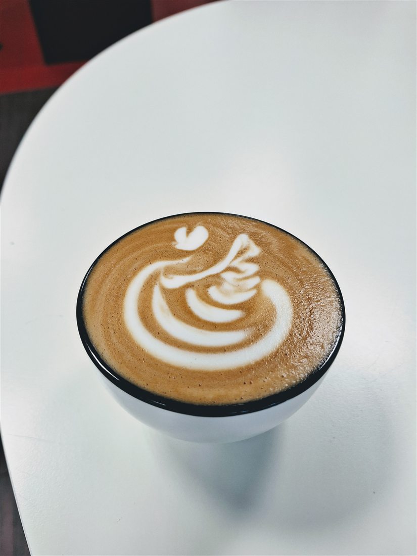 Cappuccino mit Rosetta auf weißem Tisch